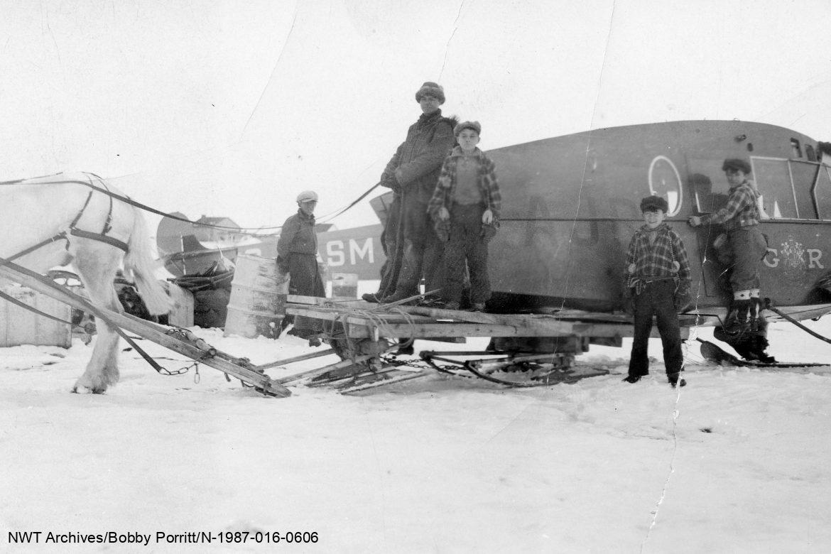 Horse-drawn sleigh and a wingless body of a RCMP Bellanca airplane that had crashed in Fort Resolution, 1930.