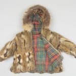 Une veste d’écureuil reconvertie à partir de la doublure d’un manteau en velours noir offert par Billy McNeill à sa première épouse en 1916. La seconde épouse de Billy, Eleonor Jeremie, a créé cette veste pour enfant en 1924. Portée par des générations de la famille McNeill, la petite veste a été donnée au Centre du patrimoine septentrional Prince-de-Galles en 1995.