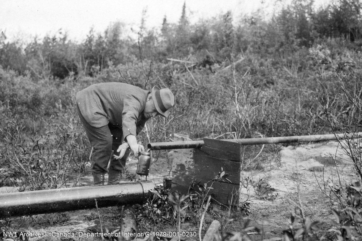 Le major D. L. Mckeand prélevant un échantillon de pétrole du puits de l’Imperial Oil à Fort Norman (maintenant Tulita), juin 1921. 