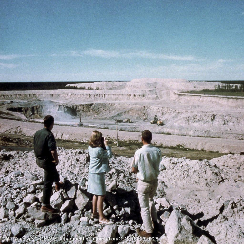 Trois personnes observent la mine à ciel ouvert de Pine Point, 1967. La ville a cessé d’exister quand la mine a arrêté d’être rentable. 