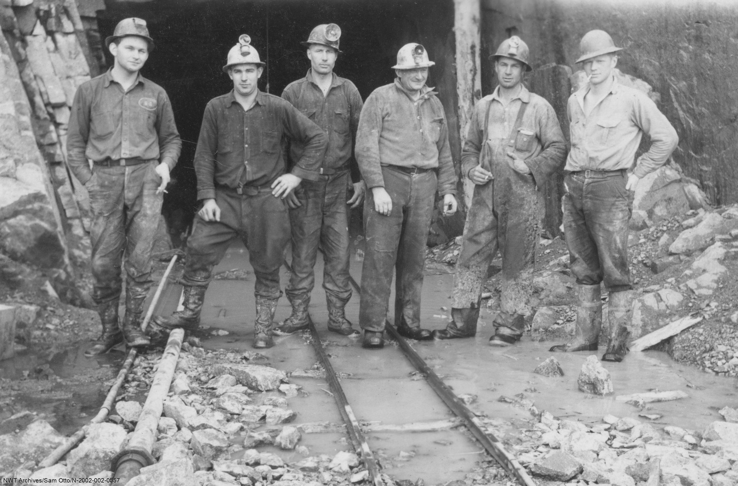 Mineurs sur des rails devant une entrée de mine au Grand lac de l’Ours, années 1930-1940.