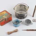 Une collection d’objets trouvés par des archéologues dans la cabane de William Hoare sur la rivière Thelon. Hoare a été le premier biologiste du gouvernement à arpenter le refuge faunique Thelon en 1928-1929. Les articles comprennent un récipient pour poêle Primus, un pot en aluminium, une bougie, des tasses en émail, une boucle, un os de caribou et une lime.