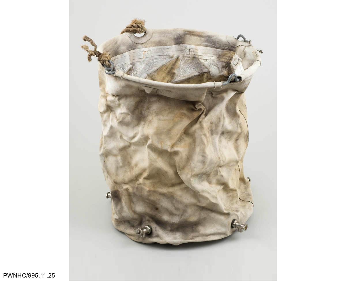 Sac de purification d’eau en toile caoutchoutée provenant de la mine Beaulieu. Cinq robinets sont présents au fond du sac qui doit être suspendu à un trépied pour être utilisé. Ce type de sac est connu sous le nom de sac Lyster, d’après William Lyster du Corps médical de l’armée américaine qui, en 1917, a conçu une méthode de traitement de l’eau dans des sacs grâce à une solution d’hypochlorite de calcium.